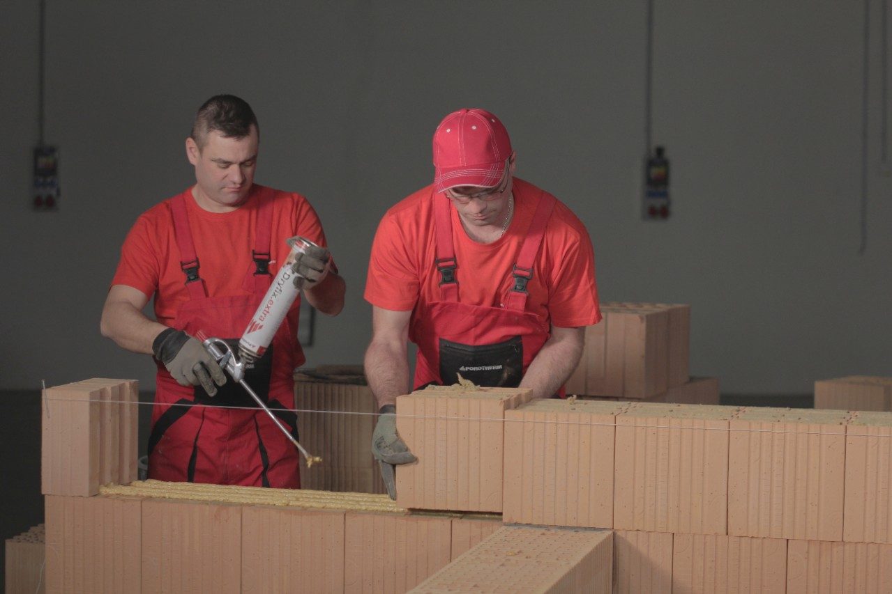 Two bricklayers laying Porotherm T Profi bricks with Porotherm Dryfix
